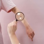 Dermatologist examining mole on patient's back in clinic